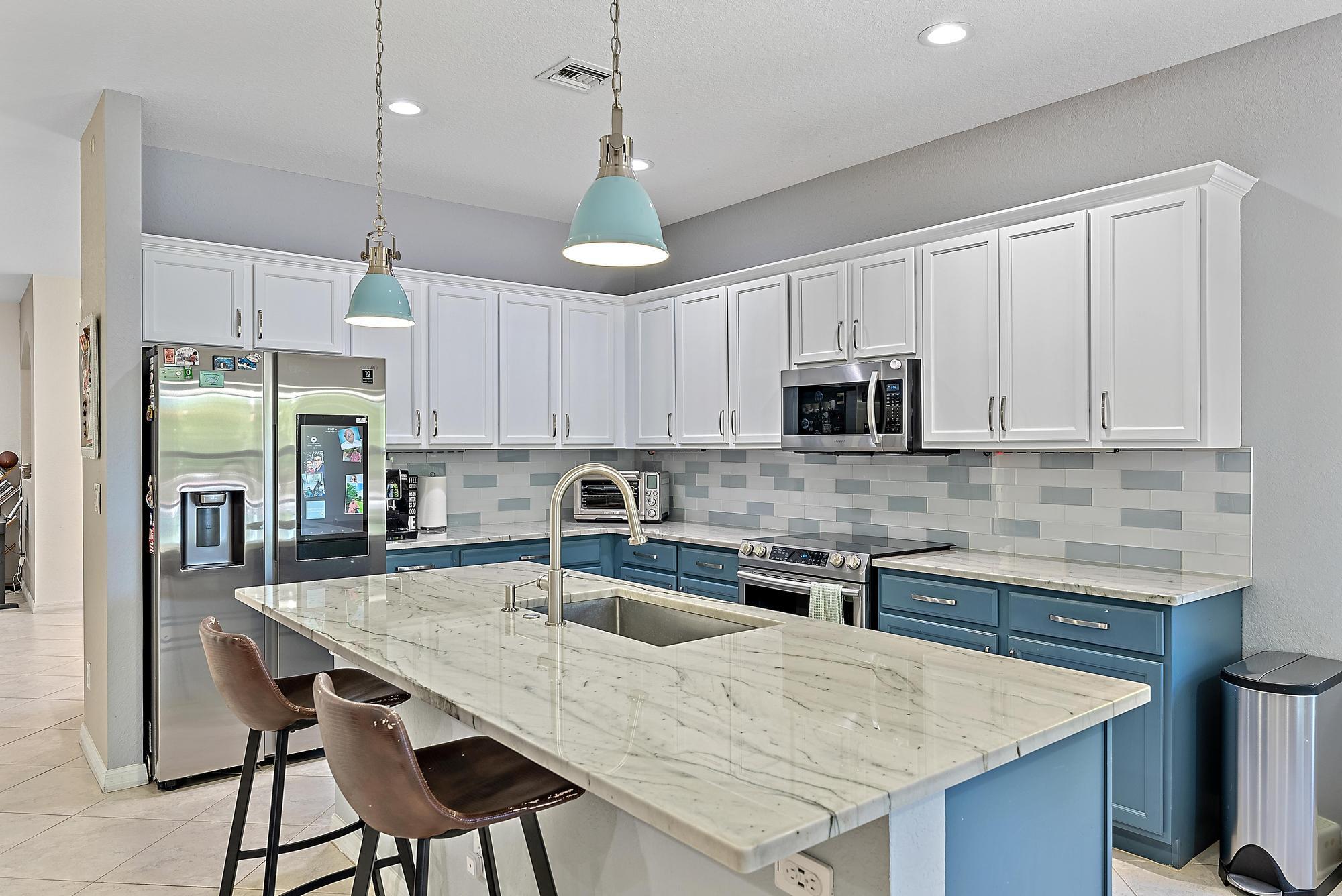 119 Whale Cay Way Jupiter, FL 33458 - Photo 6 of 46 a kitchen with stainless steel appliances granite countertop a table chairs sink refrigerator and microwave