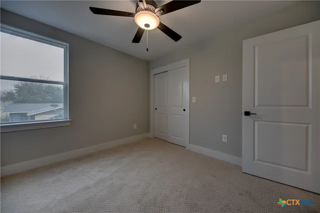 an empty room with windows and fan