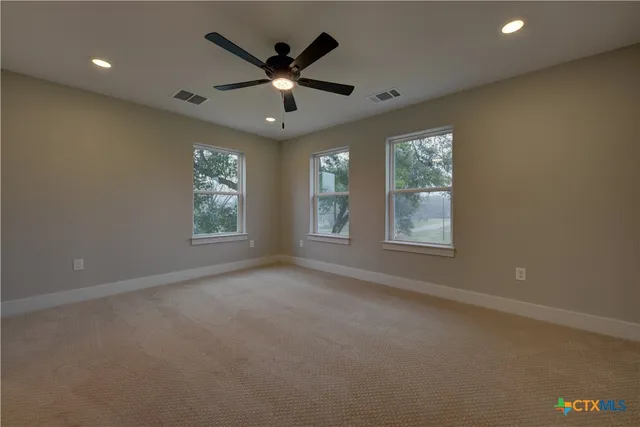 an empty room with windows and ceiling fan