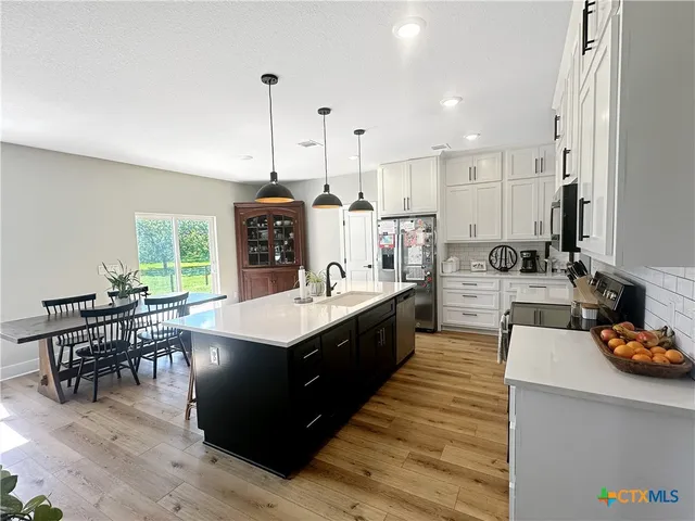 a large kitchen with kitchen island a large counter space a sink appliances and a counter top space