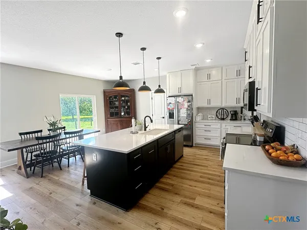 a large kitchen with kitchen island a large counter space a sink appliances and a counter top space