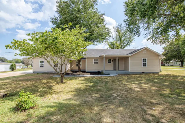 a view of a house with a yard and large tree