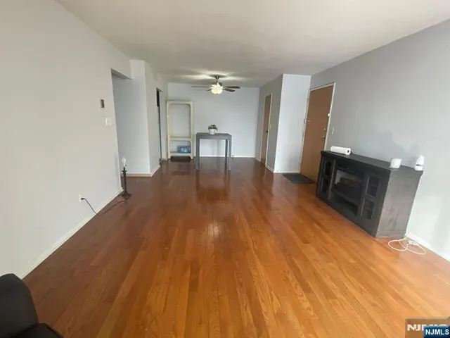 a view of empty room with wooden floor and fan