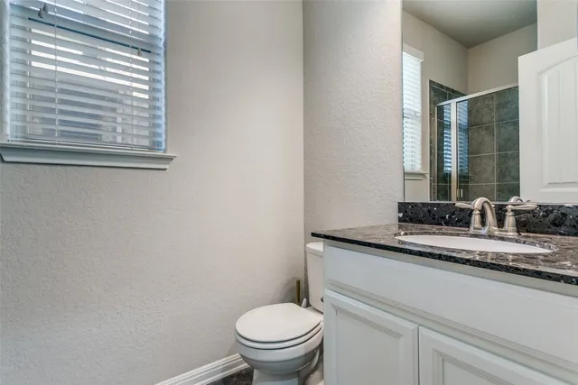 a bathroom with a granite countertop toilet sink and mirror