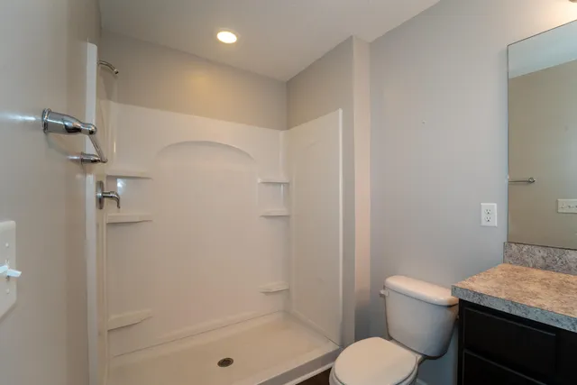 a bathroom with a granite countertop toilet a sink and shower