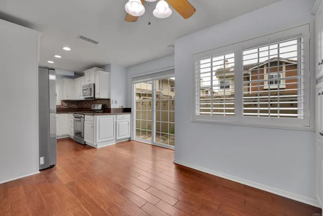 a open kitchen with granite countertop a stove top oven a sink dishwasher a dining table and cabinets with wooden floor