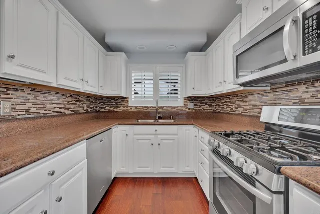 a kitchen with granite countertop a stove and white cabinets