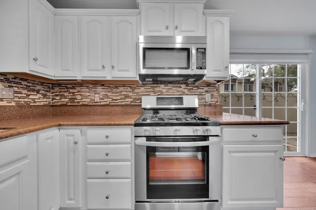 a kitchen with stainless steel appliances granite countertop a stove microwave and cabinets
