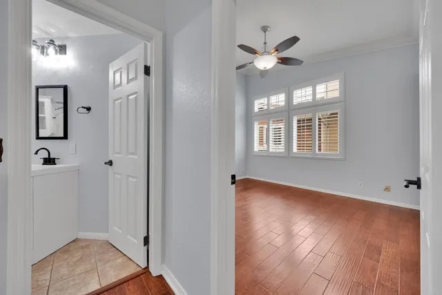 a view of a hallway with wooden floor and a ceiling fan