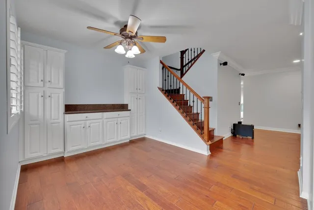 a view of an empty room with wooden floor and a ceiling fan