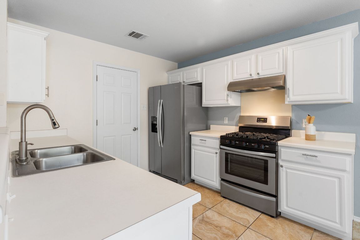 1700 Canon Yeomans Trail Austin, TX 78748 - Photo 17 of 32 a kitchen with stainless steel appliances granite countertop a stove a refrigerator and a sink with wooden cabinets