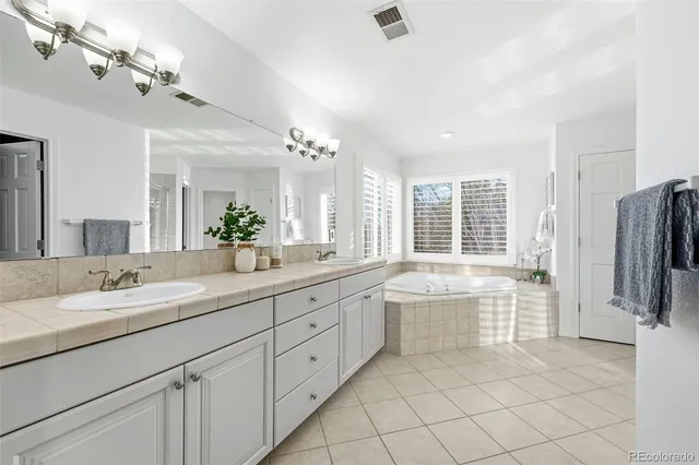 a bathroom with a granite countertop sink a large mirror a bathtub and next to a window