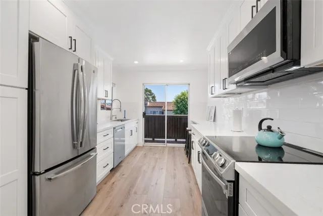 a kitchen with stainless steel appliances a refrigerator a sink and wooden cabinets