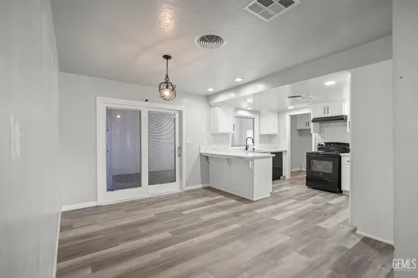 a large white kitchen with kitchen island a sink stainless steel appliances and cabinets