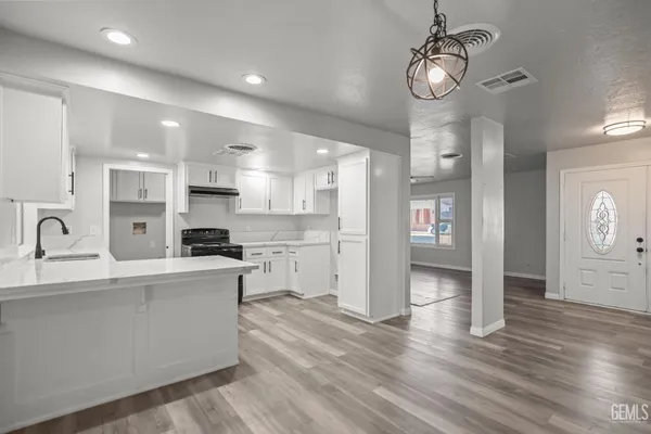 a large kitchen with stainless steel appliances granite countertop a lot of counter space and wooden floor