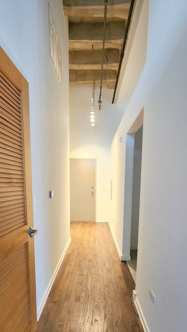 1645 West Ogden Avenue, Unit 417 Chicago, IL 60612 - Photo 3 of 19 a view of a hallway with wooden floor and staircase