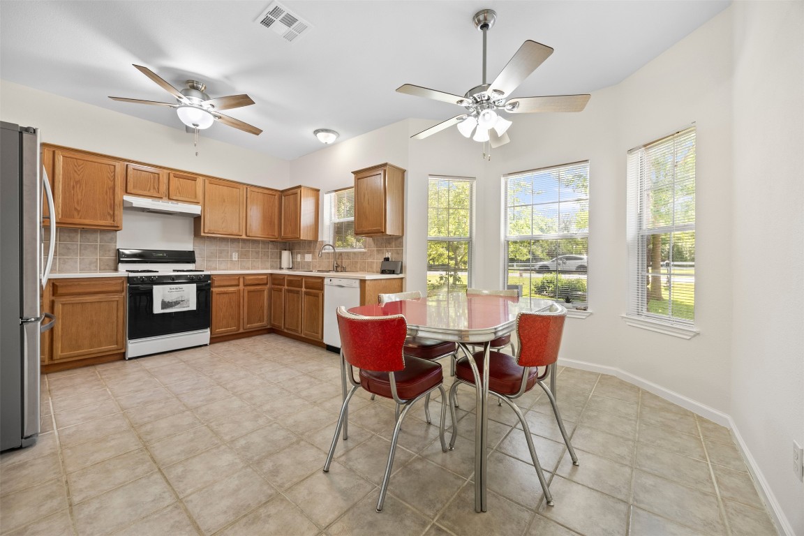 803 North Myrtle Street Georgetown, TX 78626 - Photo 11 of 40 Kitchen with gas range oven, a ceiling fan, under cabinet range hood, and freestanding refrigerator