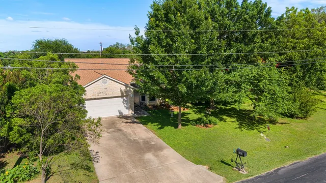 an aerial view of residential house with outdoor space and trees all around
