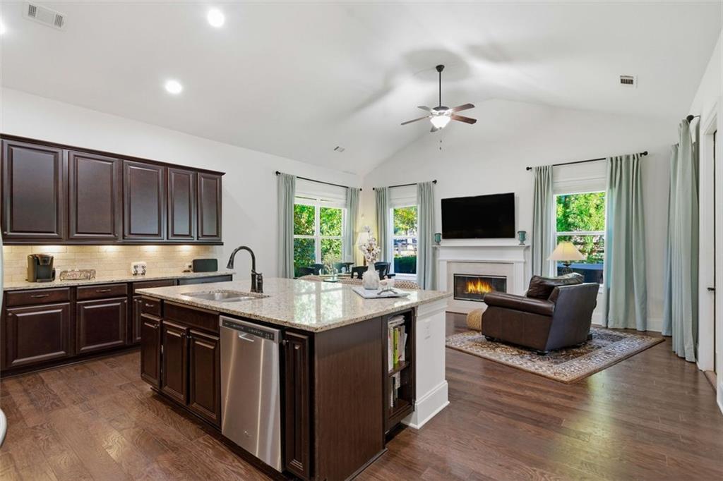 12115 Spence Way Alpharetta, GA 30004 - Photo 25 of 46 a kitchen with stainless steel appliances granite countertop a stove top oven a sink dishwasher a dining table and chairs with wooden floor