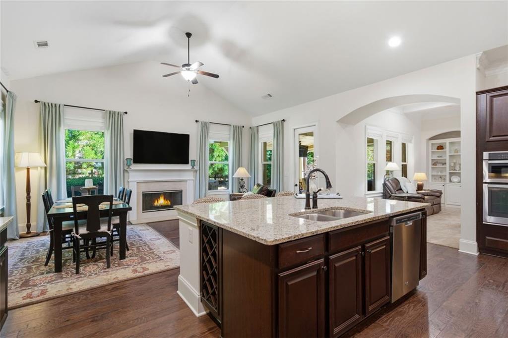 12115 Spence Way Alpharetta, GA 30004 - Photo 5 of 46 a open kitchen with stainless steel appliances granite countertop a stove top oven a sink dishwasher a dining table and chairs with wooden floor