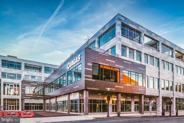 a front view of a building with lot of cars and trees