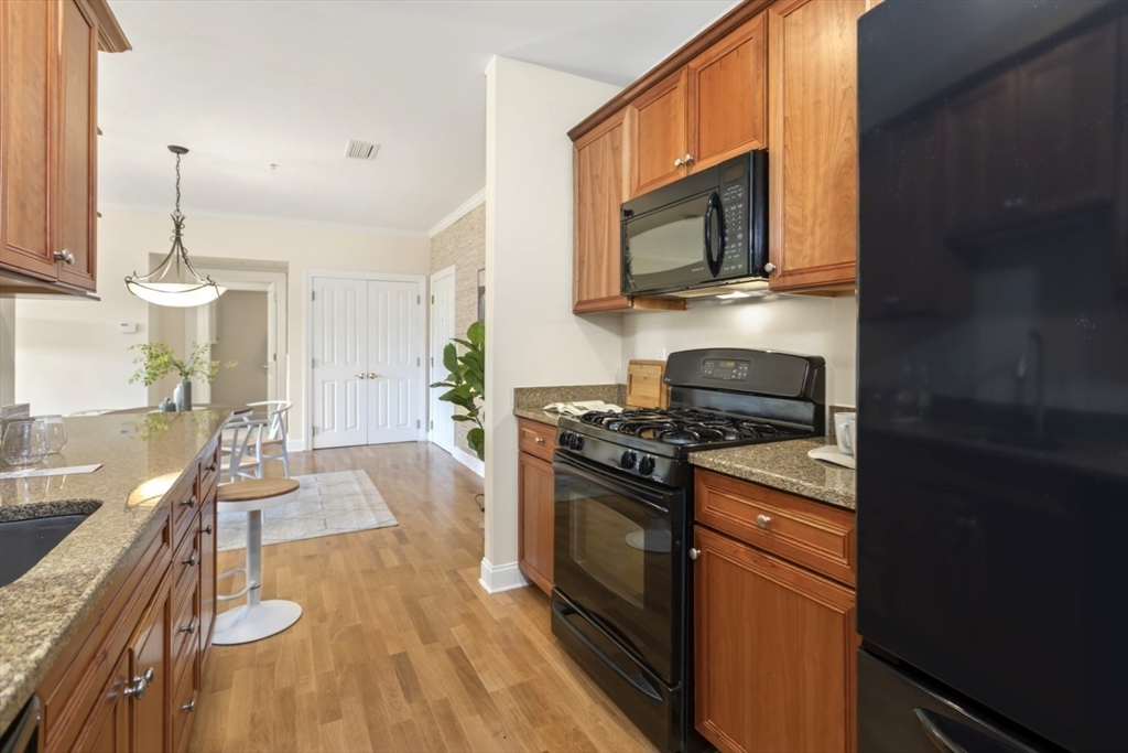 248 Albion Street, Unit 233 Wakefield, MA 01880 - Photo 20 of 39 a kitchen with stainless steel appliances granite countertop a stove a sink and a microwave