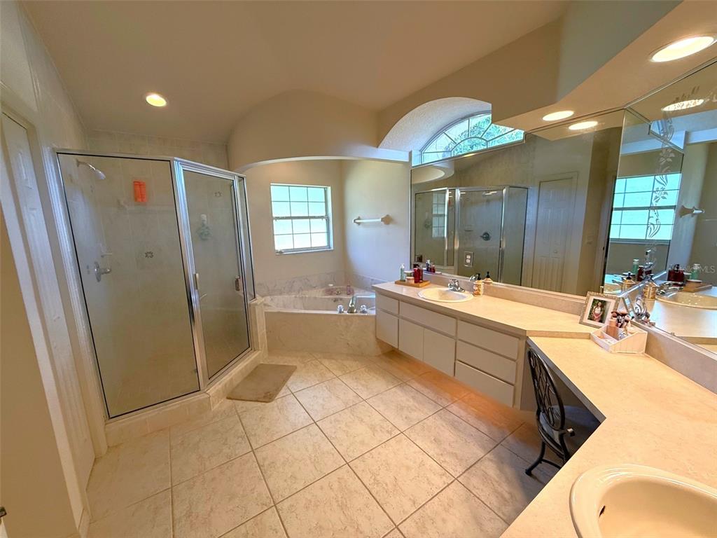 4980 Southeast 47th Terrace Road Ocala, FL 34480 - Photo 26 of 54 a bathroom with a double vanity sink a mirror a bathtub and shower