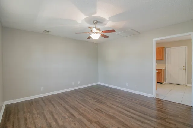 a view of a room with wooden floor and a ceiling fan