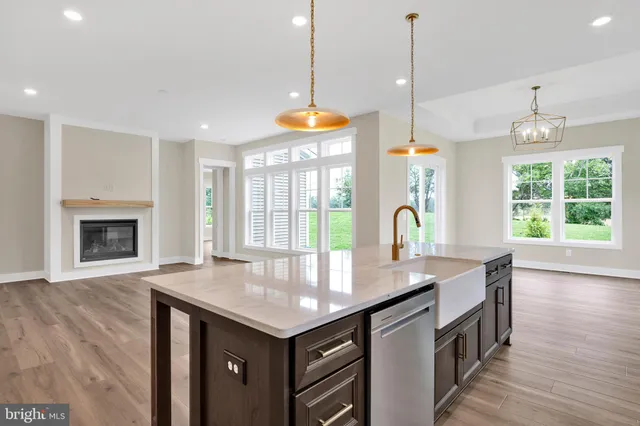 a kitchen with granite countertop a stove a sink a center island and wooden floor