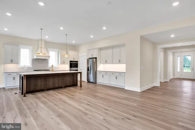 a large white kitchen with kitchen island wooden floors and a sink
