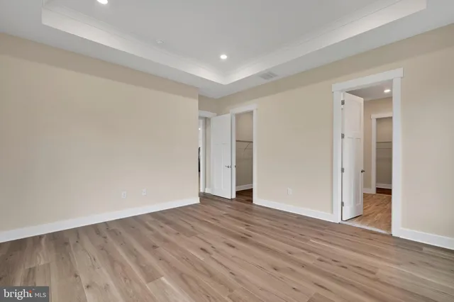 a view of an empty room with wooden floor and closet