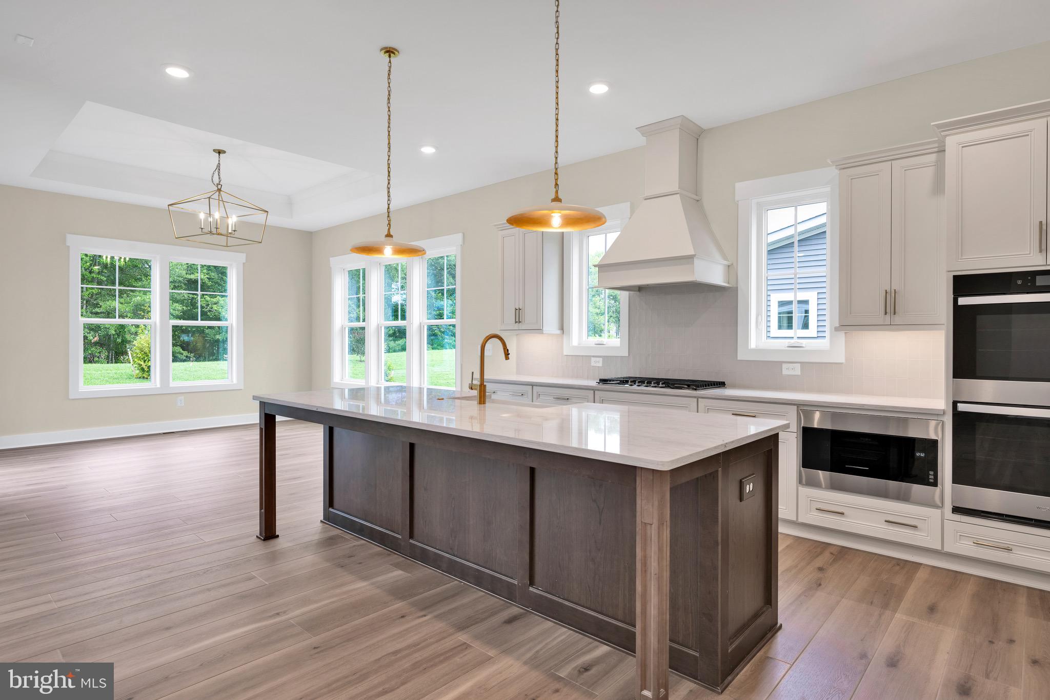 23412 East Gate Drive Frankford, DE 19945 - Photo 10 of 28 a kitchen with kitchen island granite countertop a stove a sink and wooden floors