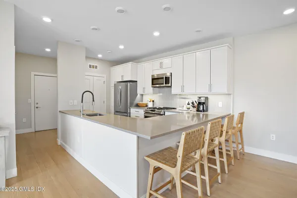 a large white kitchen with sink a stove a microwave and cabinets