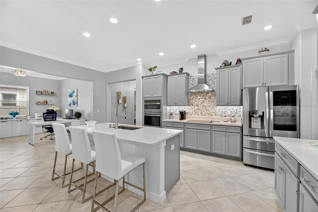 16805 Banner Shell Place Wimauma, FL 33598 - Photo 12 of 44 a kitchen with stainless steel appliances kitchen island granite countertop a refrigerator and a stove top oven