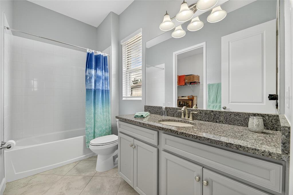 16805 Banner Shell Place Wimauma, FL 33598 - Photo 29 of 44 a bathroom with a granite countertop sink a toilet and a mirror