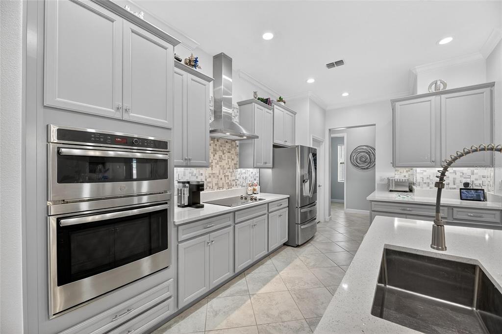 16805 Banner Shell Place Wimauma, FL 33598 - Photo 7 of 44 a kitchen with stainless steel appliances kitchen island granite countertop a stove a sink and a microwave