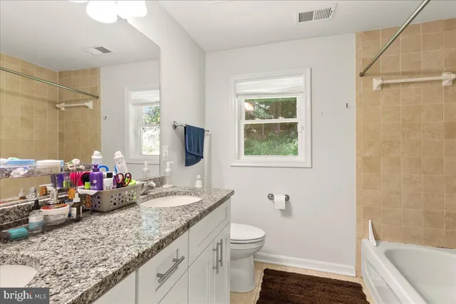 a bathroom with a granite countertop sink a mirror a bathtub and shower