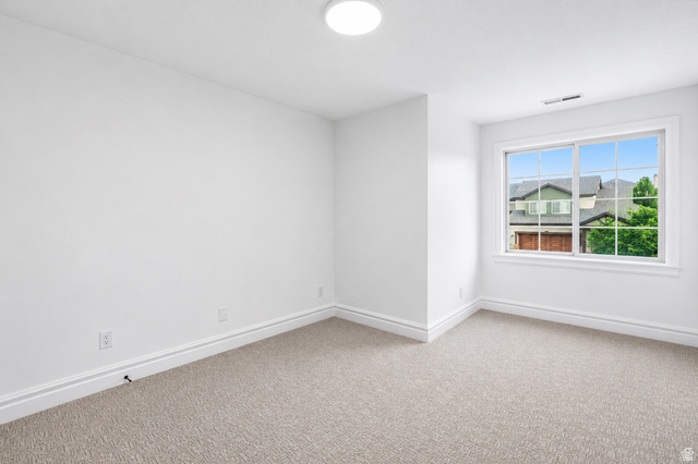 1429 Chateau Ridge Way Sandy, UT 84092 - Photo 18 of 22 Bright room featuring a large window, plush carpet flooring, white baseboards, and a flush-mount ceiling light fixture