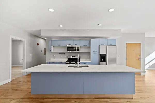 a large white kitchen with kitchen island a sink stainless steel appliances and cabinets