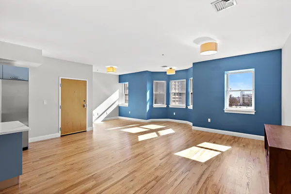 a view of empty room with wooden floor and fan