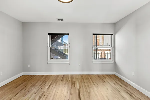 an empty room with wooden floor and windows