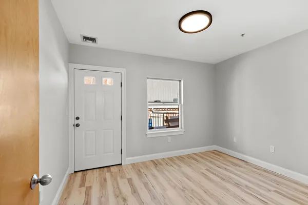 an empty room with wooden floor and windows
