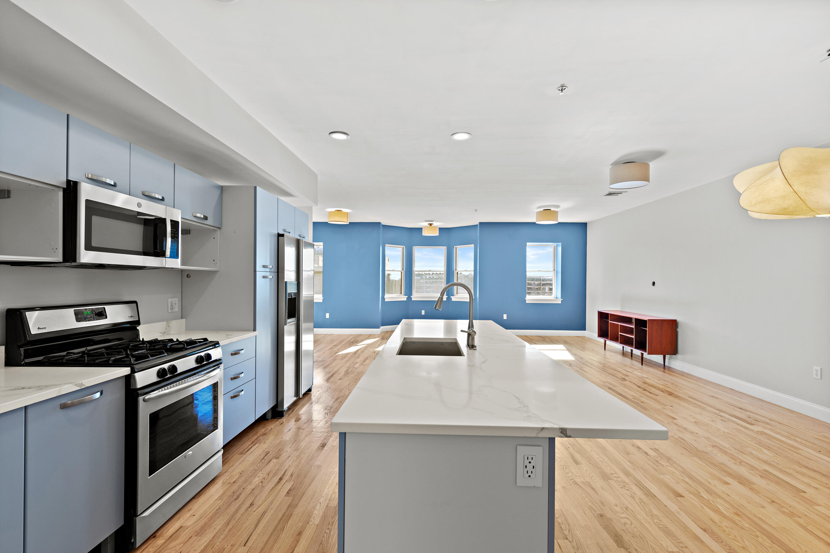 877 Harrison Avenue, Unit 7 Boston, MA 02118 - Photo 6 of 34 a kitchen with stainless steel appliances a kitchen island hardwood floor sink stove dining table and chairs