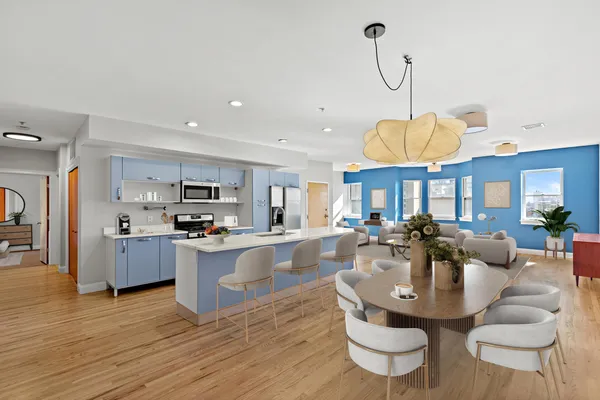 a living room with stainless steel appliances kitchen island granite countertop a stove a kitchen island a dining table and chairs with wooden floor