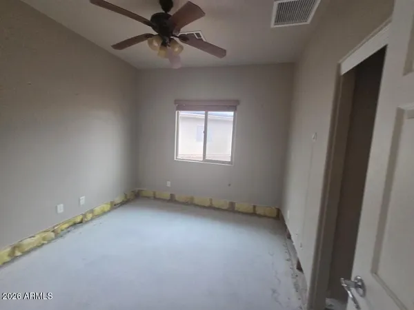 an empty room with a window and a fan