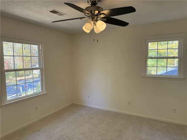 an empty room with windows and fan