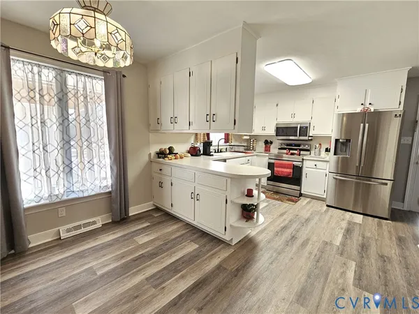 a kitchen with a sink appliances cabinets and a large window
