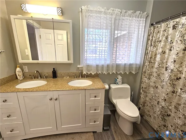 a bathroom with a granite countertop toilet sink and mirror