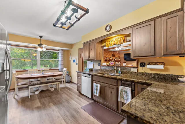 a kitchen with kitchen island granite countertop a stove a sink and wooden cabinets