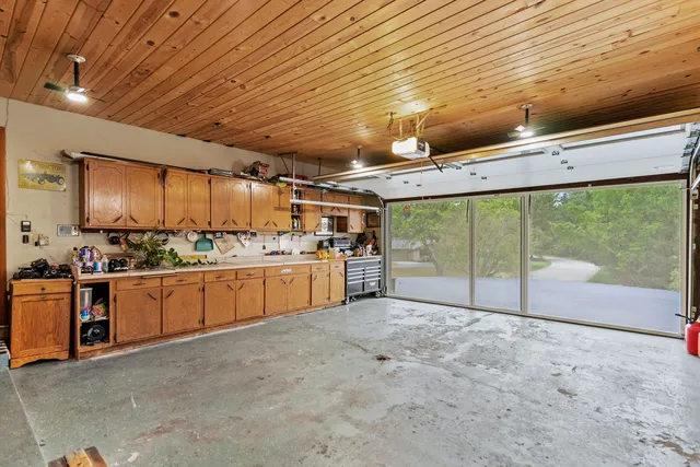 a view of a kitchen with stainless steel appliances wooden cabinets a sink and a fireplace